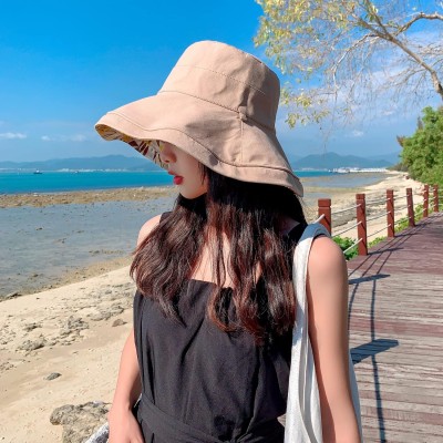 Woman wearing a wide brim reversible sun hat with UV protection